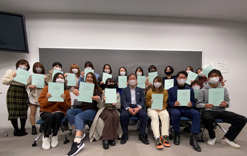 蔡易（後排左七）與武蔵野大學同學手持學習成果——畢業論文與教授合照