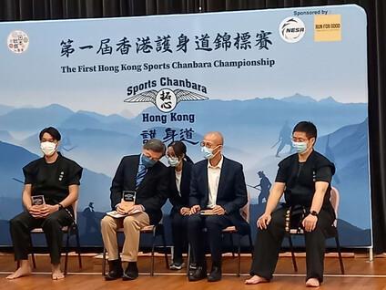 李偲翹（後排）於一項比賽活動中為岡田健一大使（左二）擔任翻譯